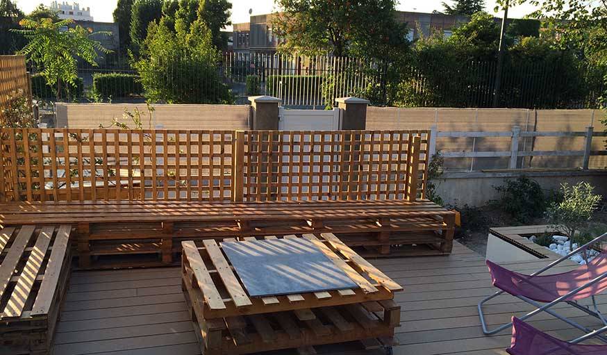 La terrasse après travaux, avec des bancs et une table sur roulettes fabriquées en palettes.