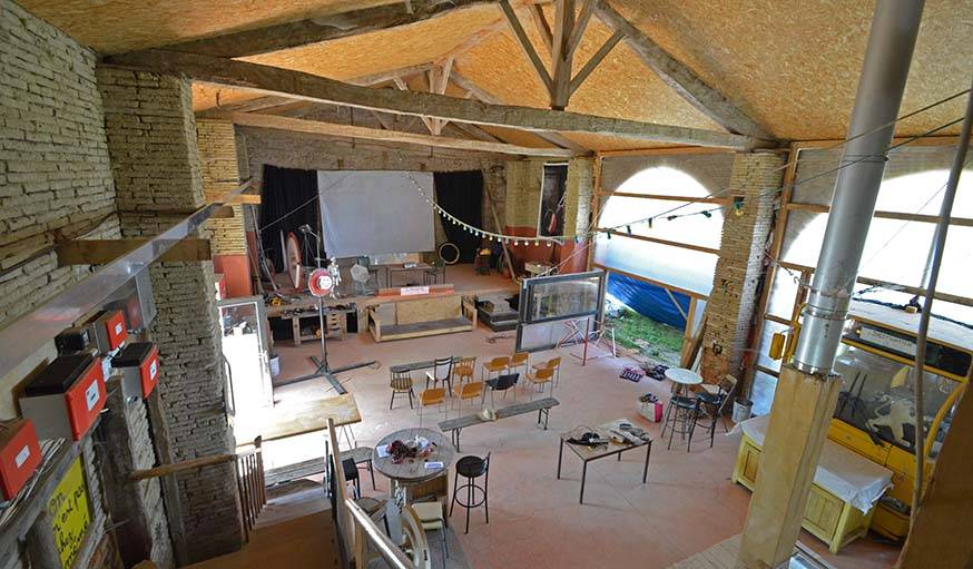 La grange de Lîlegal. Sur la scène, un rétroprojecteur servira d'écran au rétroprojecteur pendant le rassemblement des artisans poêliers.