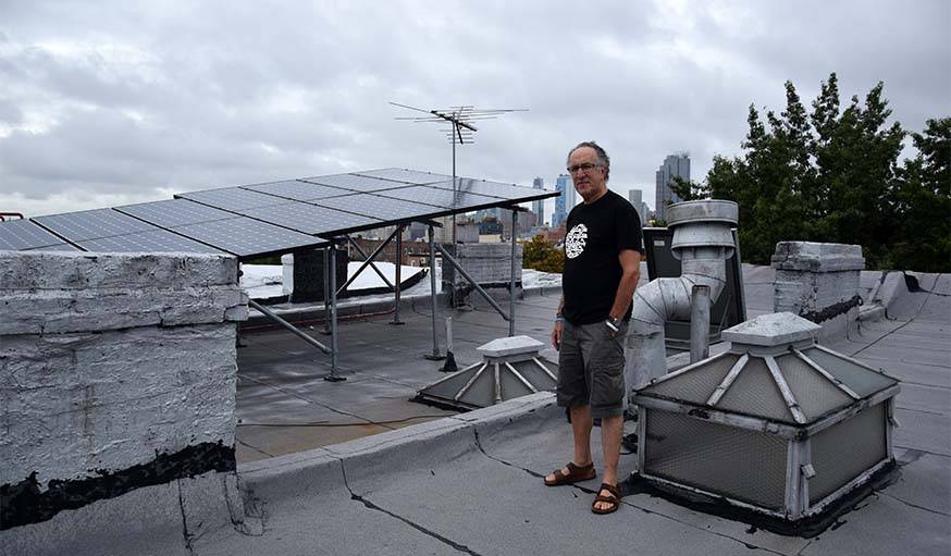 Eric Frumin devant ses panneaux solaires, et en arrière-plan, New-York.