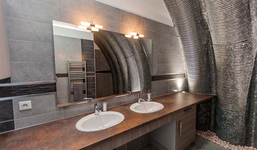 Dans cette salle de bains, la voûte en acier imprime son style.