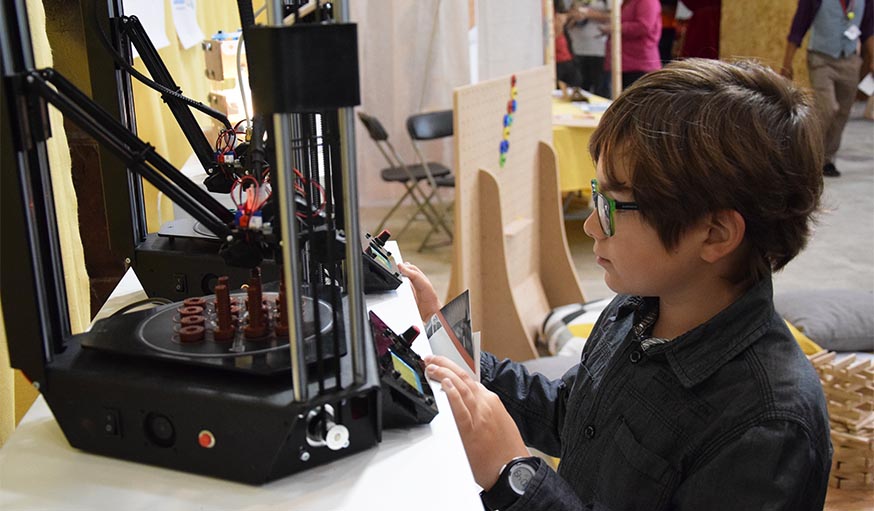 Gaël, 10 ans, observe l'impression en 3D des boulons OpenFabrick. 