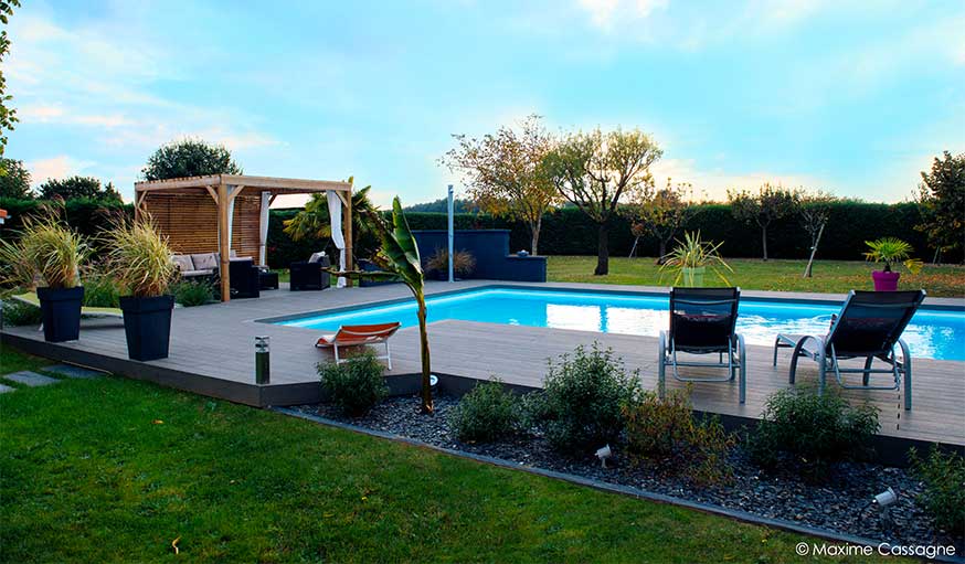 Piscine rénovée avec un nouveau revêtement, des plantes, de la lumière et une pergola