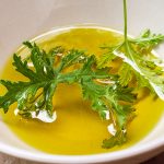 Une feuille de citronnelle repose dans de l'huile pour faire un anti moustique naturel et fait maison