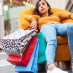 Une femme qui vient de faire beaucoup de shopping semble fatiguée dans un fauteuil