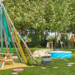 un tipi pour enfants réalisé avec des branches et des chutes de tissu dans un jardin