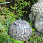 Une boule à facettes décorative dans un jardin près d'une statue de tête de bouddha