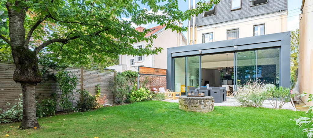 Une extension avec baie vitrée qui donne sur un petit jardin dans une maison de ville